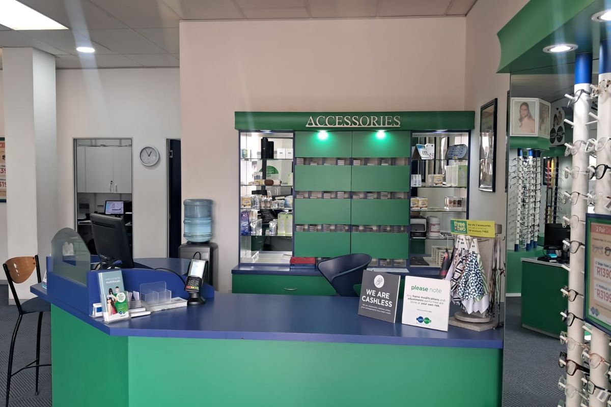 A retail optometry reception area featuring a built-in service counter, integrated display shelving for accessories, and professional recessed lighting.