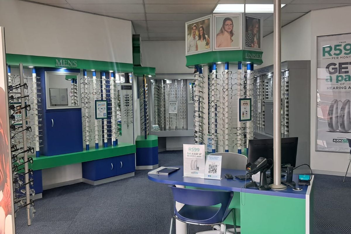 A retail optometry store interior featuring custom built-in display shelving units, a central service counter, and professional retail lighting.