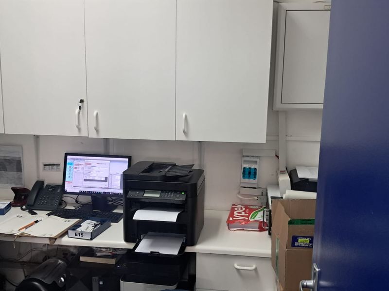 A functional office space featuring built-in white cabinetry and a practical desk workspace, suitable for administrative or retail back-office operations.