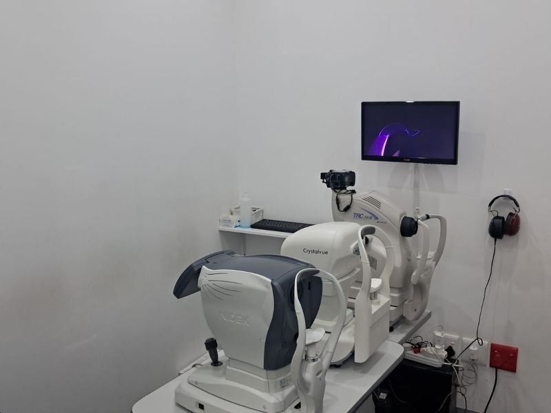 A clinical examination room featuring specialized diagnostic equipment, wall-mounted display, and functional electrical infrastructure.