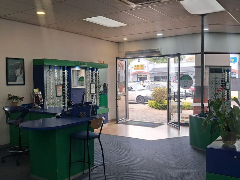 Retail entrance area featuring a built-in reception desk, display shelving, and glass doors leading to an outdoor parking area.