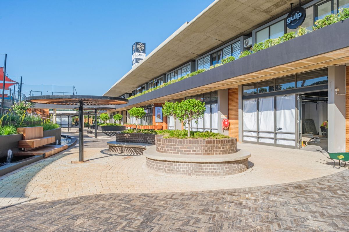 Modern commercial exterior featuring paved walkways, built-in brick planters, and a contemporary concrete overhang, providing an inviting outdoor space for restaurant patrons.
