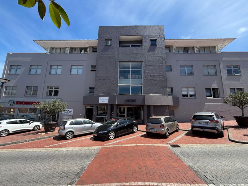 Front elevation of a multi-story commercial office building featuring a paved parking area and modern architectural facade.