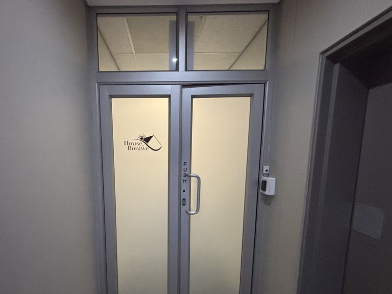 Office entrance featuring aluminium framed glass double doors with transom window and integrated access control system.