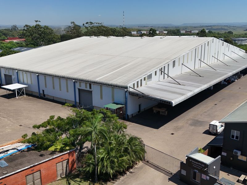 Aerial view of a large industrial warehouse facility featuring a expansive metal roof, loading bays, and paved yard space.