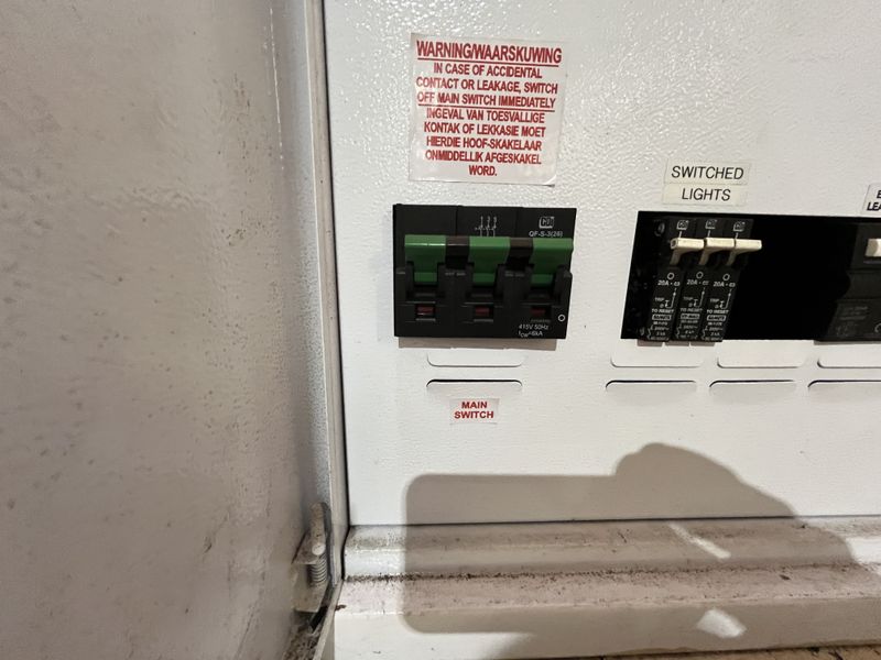 Close-up view of an industrial electrical distribution board featuring a main switch and labeled circuit breakers for lighting and power circuits.