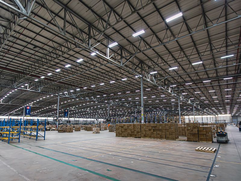 Expansive industrial warehouse facility featuring high-clearance steel truss roofing, polished concrete flooring, integrated LED lighting, and extensive fixed steel racking systems.
