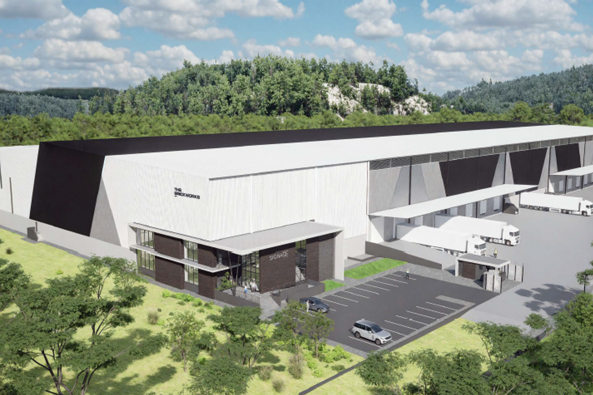 Aerial view of a modern industrial warehouse facility featuring loading docks, dedicated parking, and a secure entrance gatehouse.