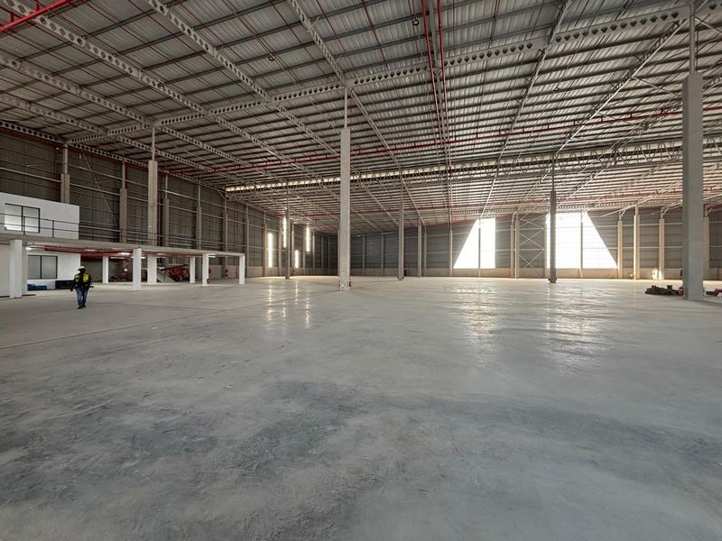 Expansive industrial warehouse space featuring high ceilings, polished concrete flooring, exposed steel structural elements, and integrated fire suppression systems.