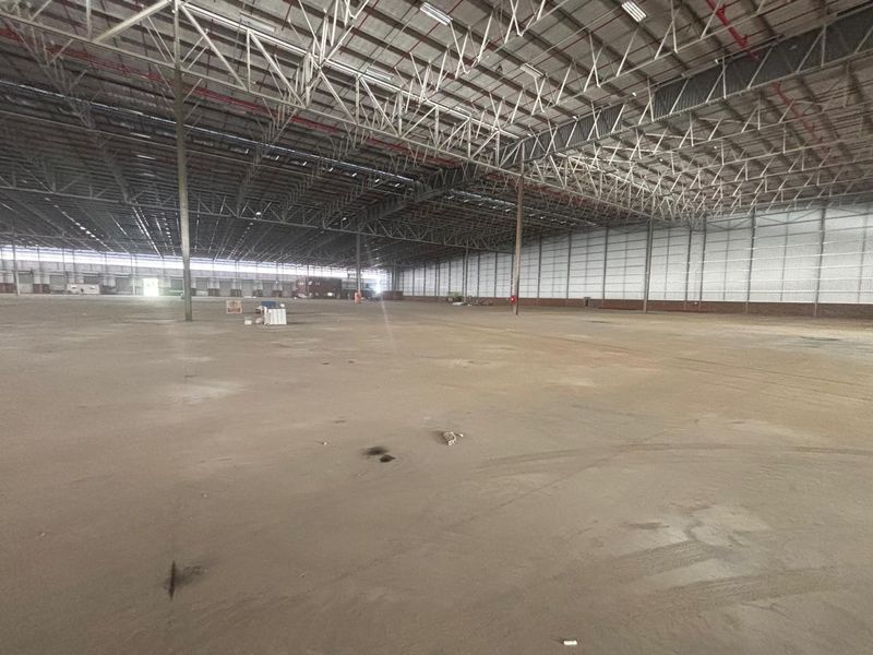 Expansive industrial warehouse space featuring high-clearance steel truss roofing, durable concrete flooring, and integrated fire sprinkler systems.