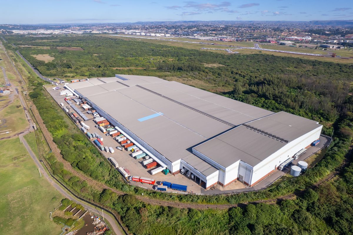 Aerial view of a large industrial warehouse facility featuring extensive loading bays, metal roofing, and a paved yard area.