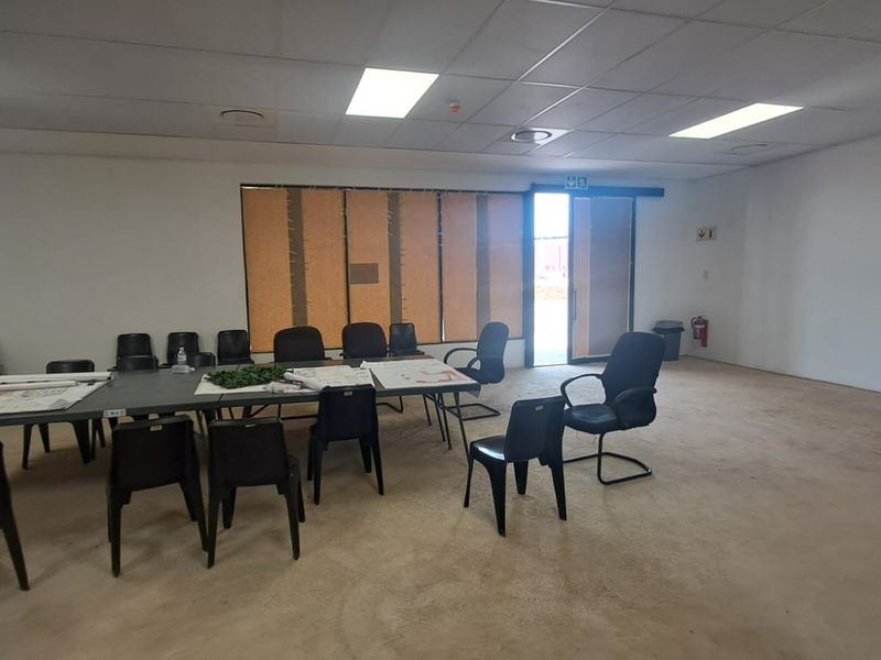 Open plan retail or office space featuring a suspended ceiling, recessed lighting, and direct access via a sliding door.