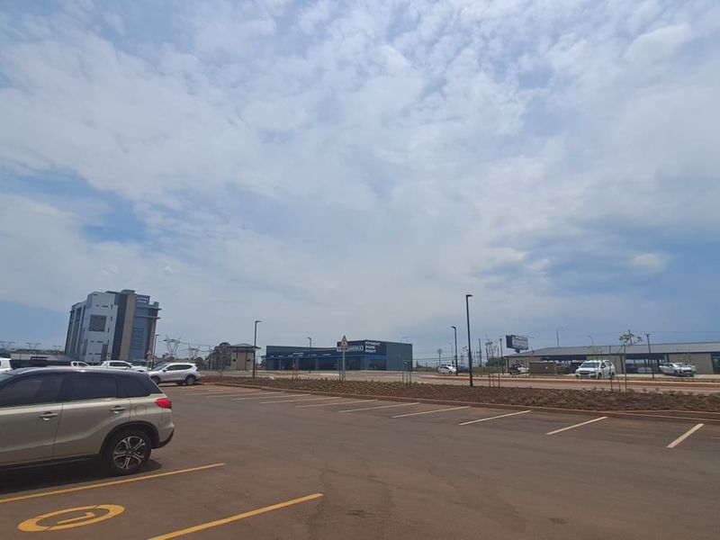 A wide-angle view of a commercial retail property featuring a large asphalt parking area and modern building facades under a clear sky.