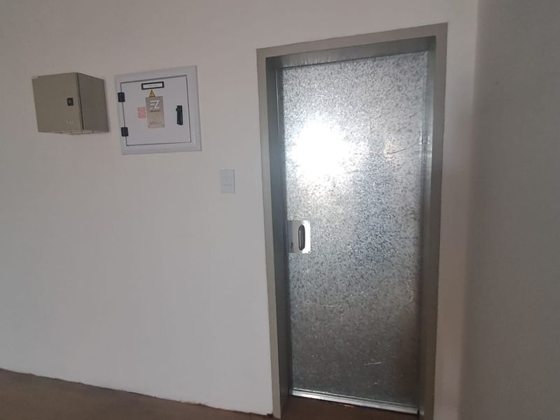 Utility area featuring a durable galvanized steel door, wall-mounted electrical distribution board, and a fire safety cabinet.