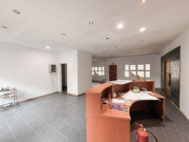 Spacious industrial office area featuring tiled flooring, recessed lighting, a built-in reception desk, and a decorative stone feature wall.