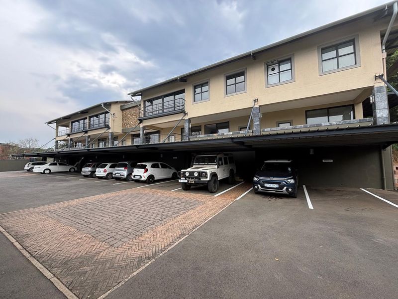 Exterior view of a multi-story office building featuring covered parking bays and upper-level balconies.