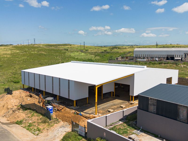 Aerial view of a modern industrial warehouse facility under construction, featuring a large steel structure and expansive open floor space.