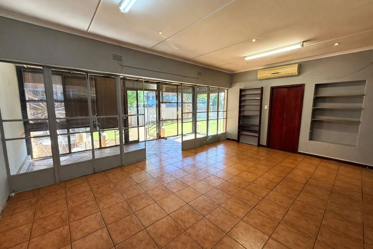 Spacious office area featuring tiled flooring, built-in shelving, air conditioning, and large glass doors providing natural light and access to the exterior.