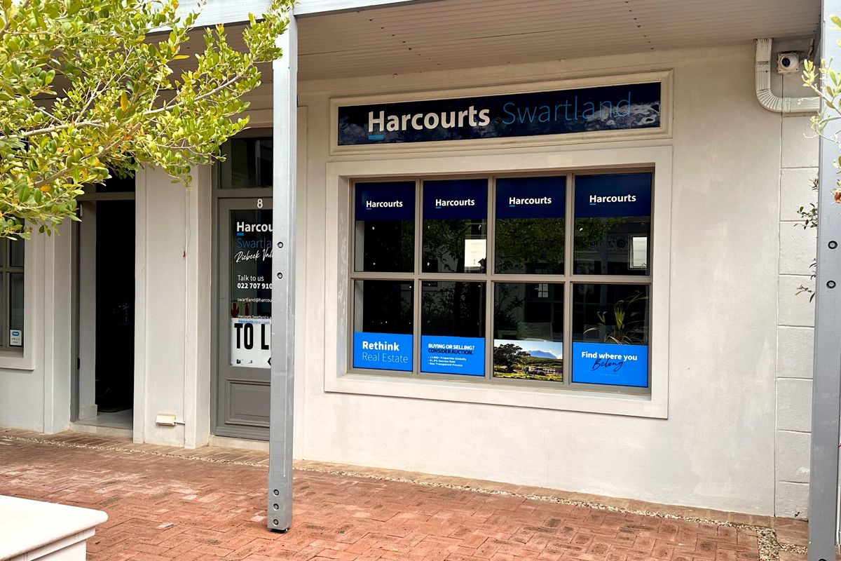 Front facade of a commercial office space featuring large display windows, covered walkway, and brick paved entrance area.