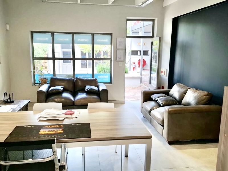 A bright and modern office space featuring large windows, tiled flooring, and a bold accent wall, providing a professional and welcoming work environment.