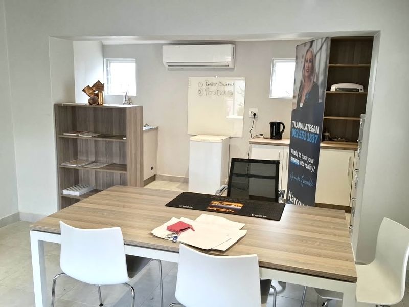 A functional office space featuring tiled flooring, built-in cabinetry, recessed shelving, and a wall-mounted air conditioning unit.
