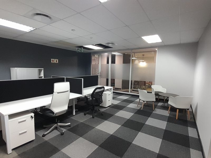 Modern office space featuring a professional layout with carpet tiles, suspended ceiling, and glass partition walls, providing a clean and functional work environment.