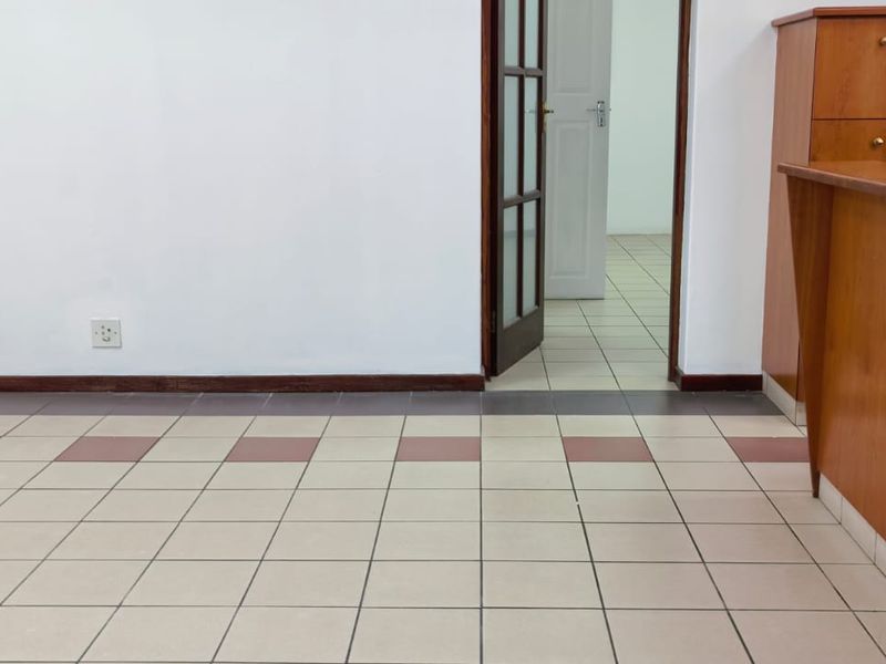 A vacant office space featuring a built-in wooden reception counter, tiled flooring, and a doorway leading to an adjacent room.