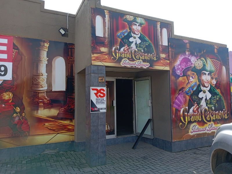 Commercial entrance facade featuring large promotional signage and security system branding, with a paved approach area.