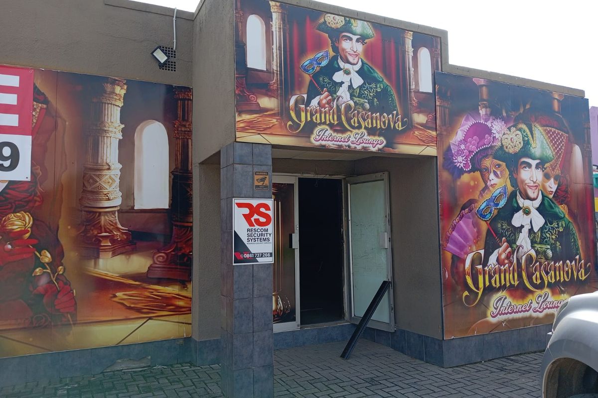 Commercial entrance facade featuring large promotional signage and security system branding, with a paved approach area.