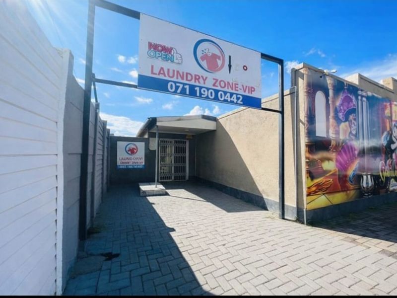 Commercial property entrance featuring paved driveway, security gate, and prominent business signage.