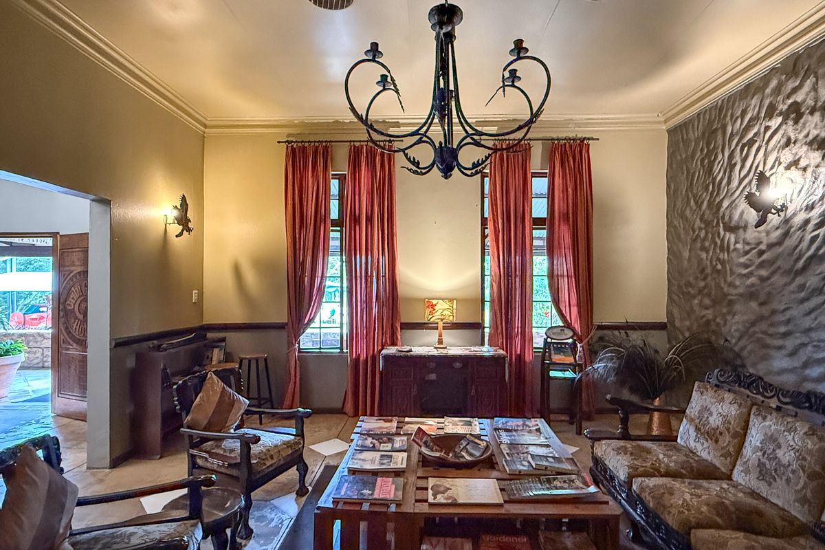 A rustic living room featuring a textured stone accent wall, crown molding, and a decorative wrought iron chandelier, offering a warm and traditional atmosphere.