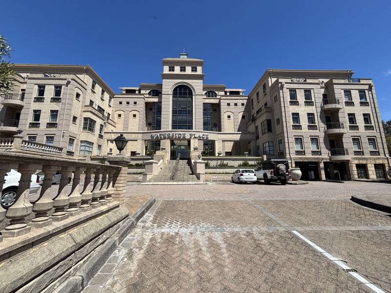 Front elevation of Waterside Place office complex featuring a grand central entrance, stone facade, and paved driveway area.