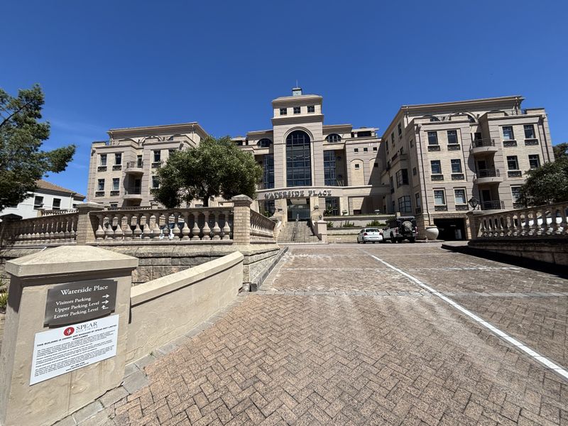 Front elevation of Waterside Place office building featuring a paved driveway, stone balustrades, and multi-story architectural facade with underground parking access.