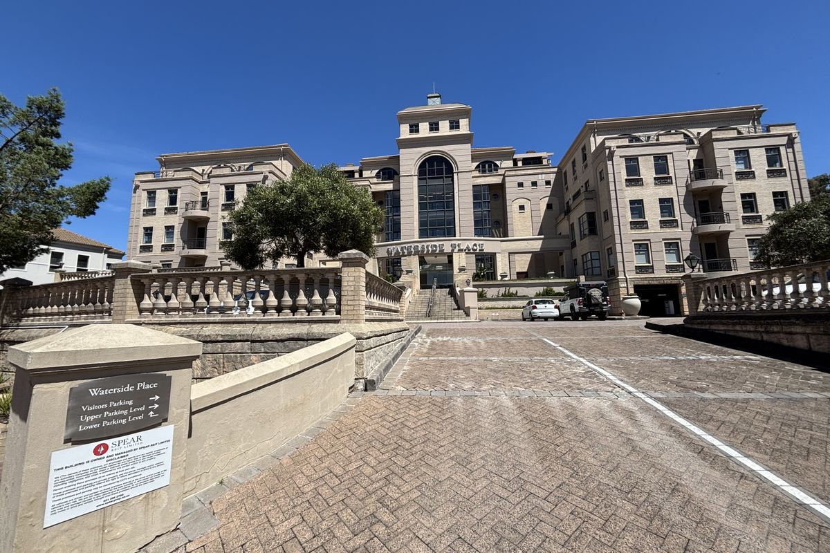 Front elevation of Waterside Place office building featuring a paved driveway, stone balustrades, and multi-story architectural facade with underground parking access.