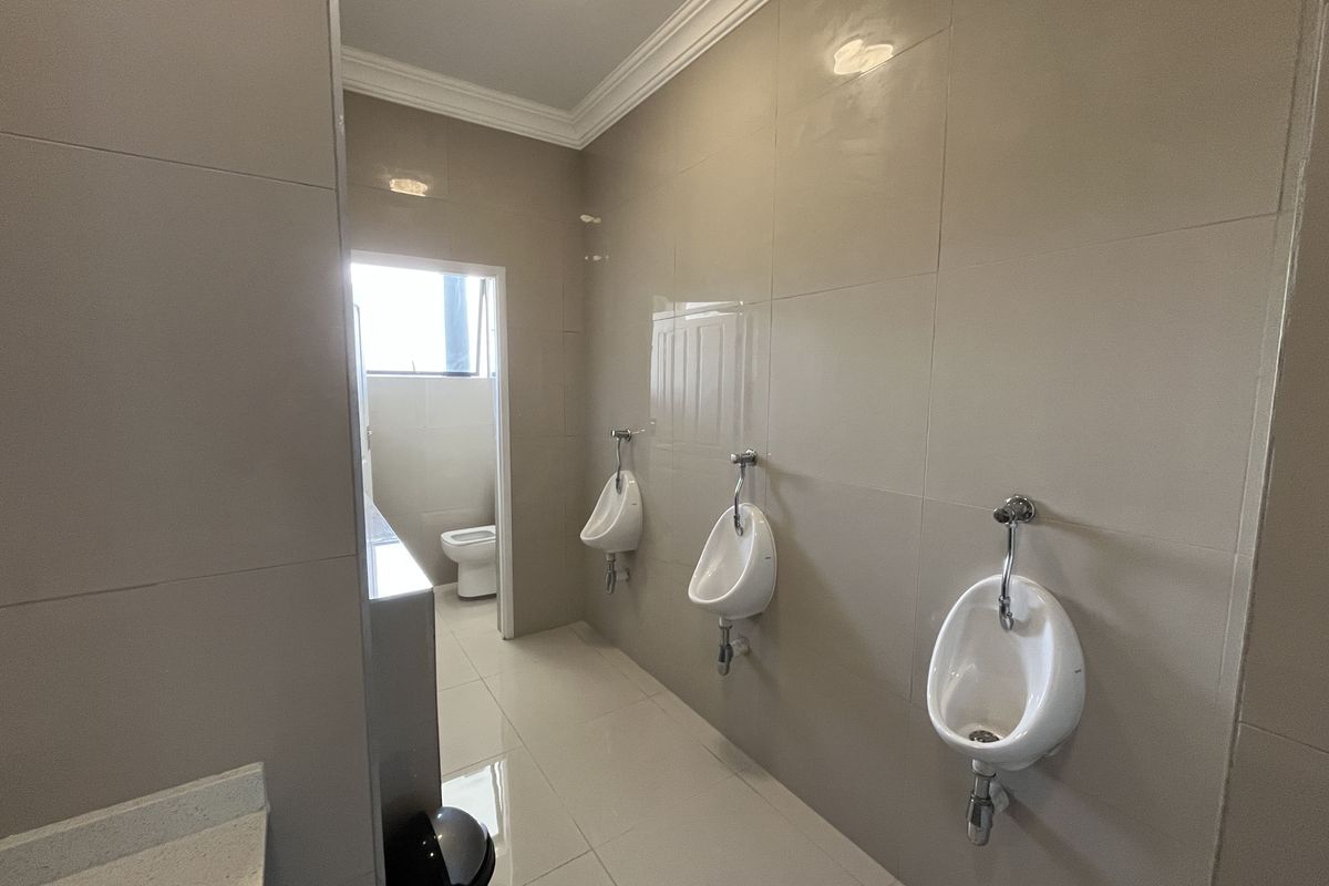 A clean, modern office restroom featuring three wall-mounted ceramic urinals and tiled wall and floor finishes.