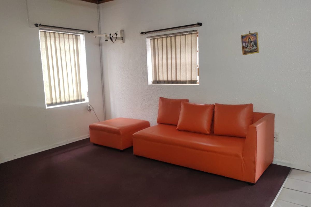 A functional living area featuring vertical blinds on windows and a combination of carpeted and tiled flooring.