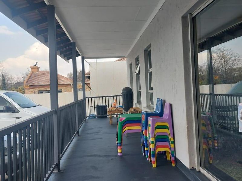 A covered outdoor patio area featuring a metal railing, painted concrete flooring, and large sliding glass doors providing access to the interior.