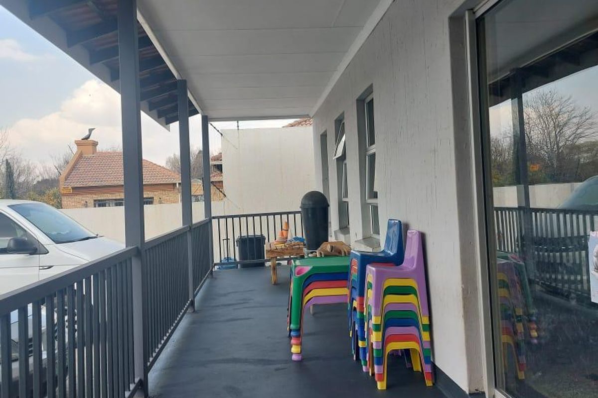 A covered outdoor patio area featuring a metal railing, painted concrete flooring, and large sliding glass doors providing access to the interior.