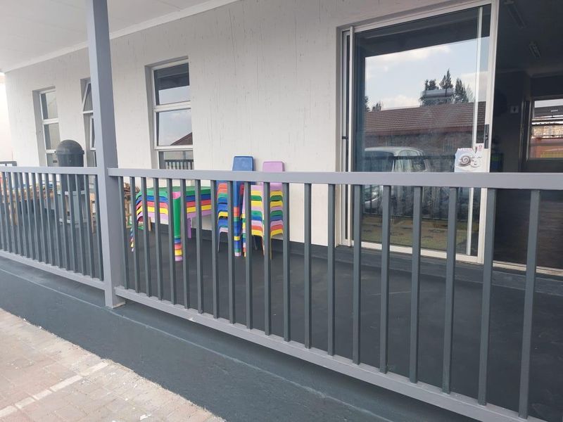 A covered outdoor patio area featuring a metal balustrade, paved flooring, and sliding glass door access to the interior.