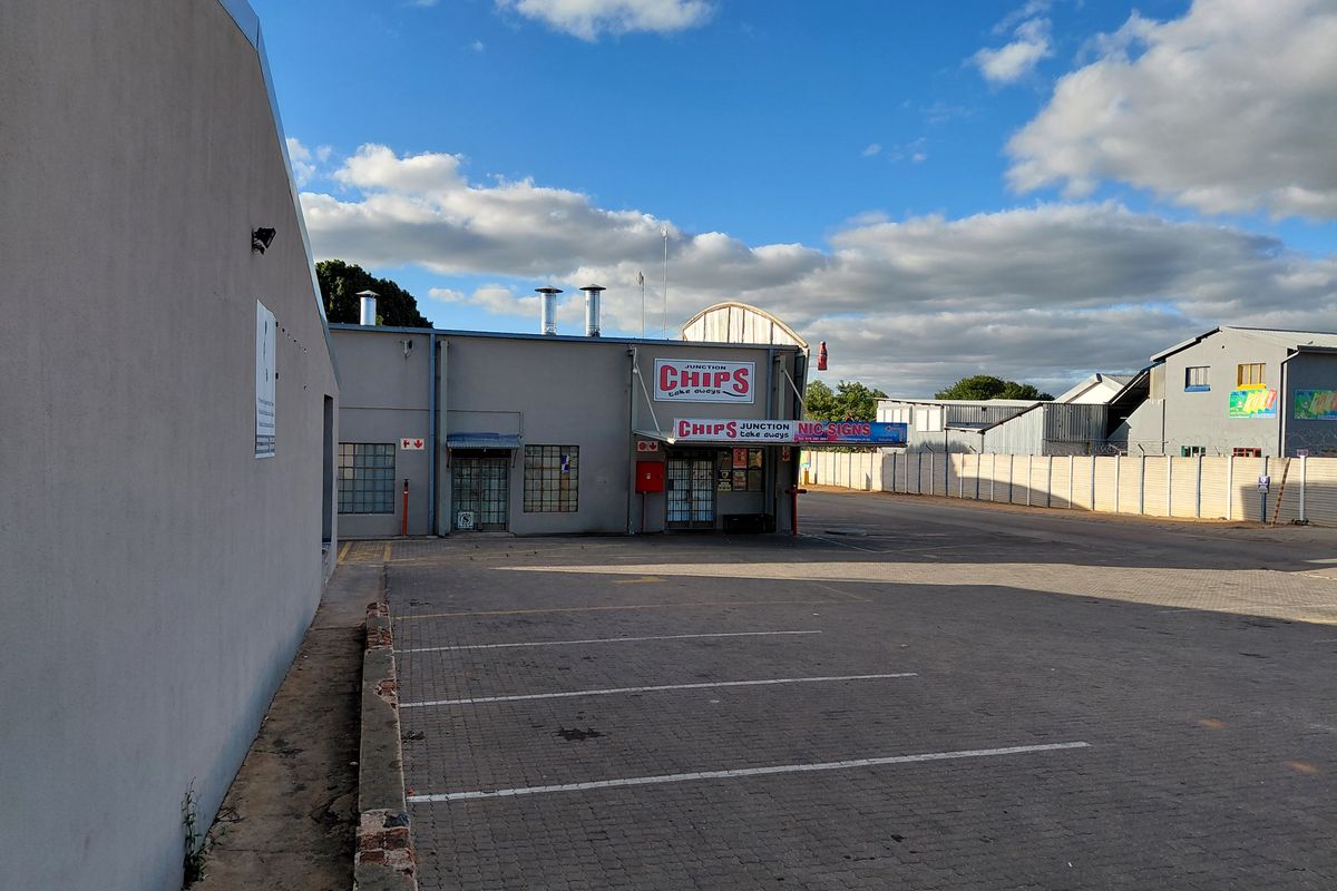 Exterior view of a commercial property featuring a paved parking area, building facade with signage, and industrial-style ventilation flues.