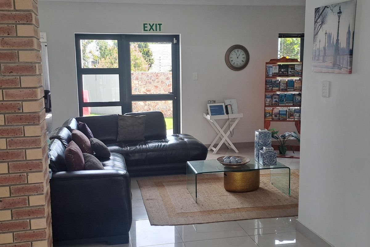 A bright living area featuring tiled floors, an exposed brick accent pillar, and direct access to the exterior through a glass door.