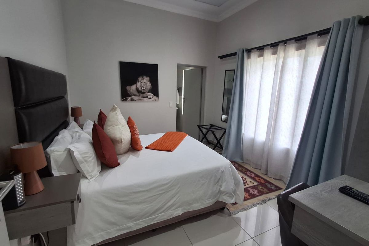 A well-maintained bedroom featuring tiled flooring, neutral wall finishes, and large windows with curtains, providing a comfortable and bright living space.
