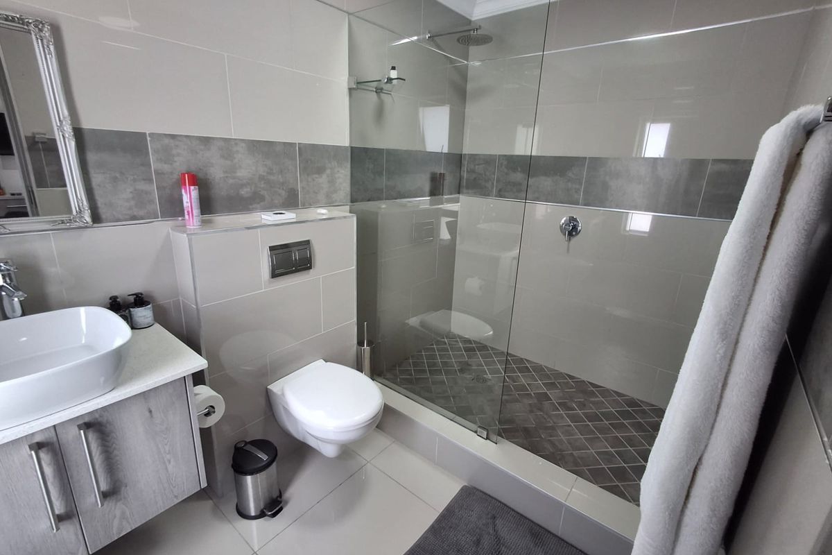 Modern bathroom featuring a wall-mounted toilet, a spacious walk-in shower with glass enclosure, and a contemporary vanity with a vessel sink.