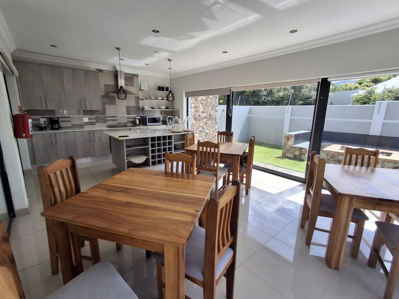 Spacious open-plan kitchen and dining area featuring modern cabinetry, a central island, tiled floors, and large sliding doors opening to a private garden.