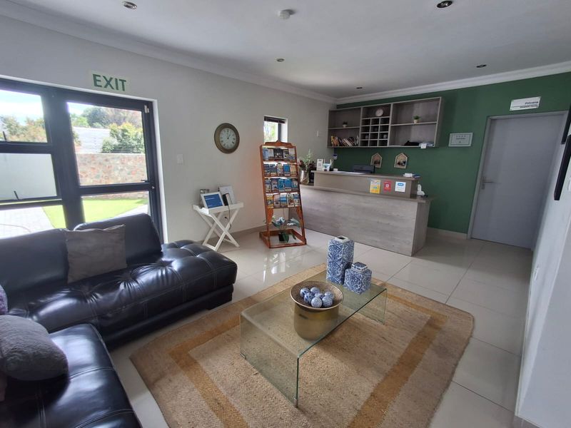 A bright and welcoming guest house reception area featuring a built-in service desk, tiled flooring, and direct access to the exterior.