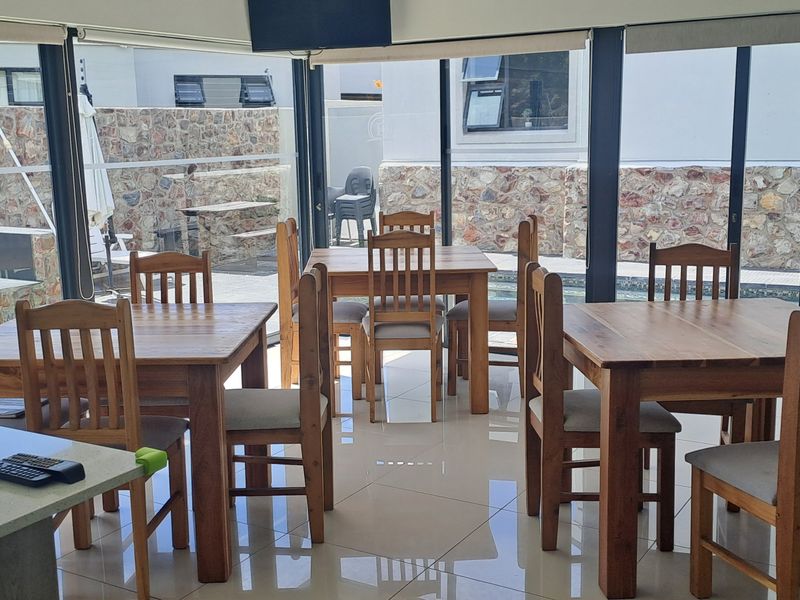 Bright open-plan dining area featuring large glass sliding doors that provide seamless access to the outdoor patio and fire pit area.