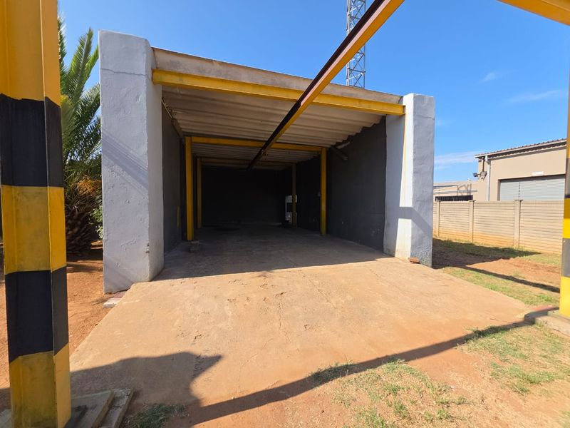 A functional open-plan commercial garage or utility space featuring a steel frame structure and concrete flooring, suitable for storage or workshop use.