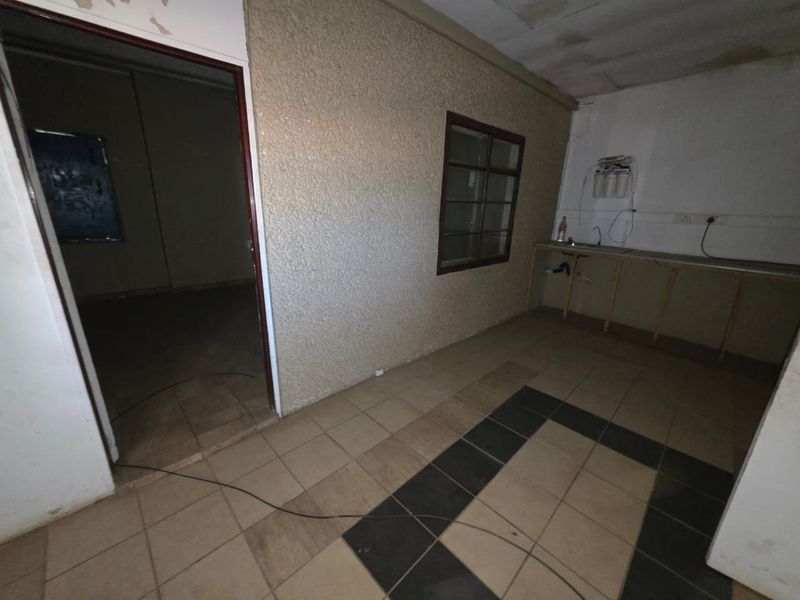 A basic utility or kitchenette area featuring tiled flooring, a simple counter structure, and a water filtration system, requiring significant renovation and cosmetic updates.