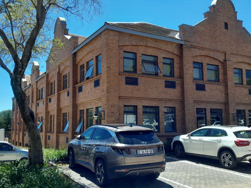 A well-maintained multi-story office building featuring a classic face brick facade, gabled architectural details, and dedicated paved parking.