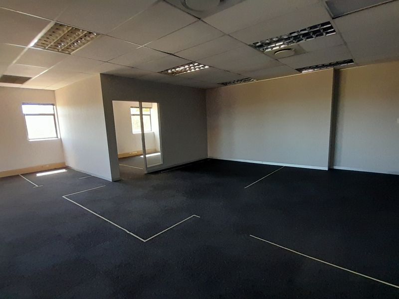 Spacious open-plan office area featuring suspended ceilings, recessed lighting, and carpeted flooring with an internal glass partition.